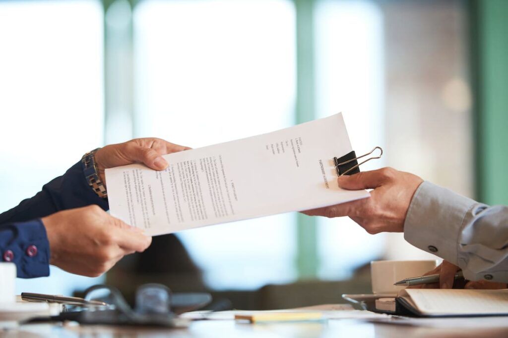 Manos intercambiando un documento laboral sobre un escritorio: reglamentación del Fondo de Asistencia Laboral (Decreto 408/2026).