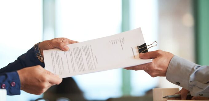 Manos intercambiando un documento laboral sobre un escritorio: reglamentación del Fondo de Asistencia Laboral (Decreto 408/2026).